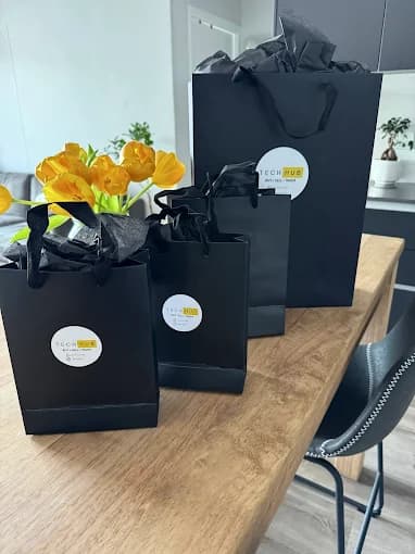 Tech Hub branded packaging: black bags with the Tech Hub seal, tied with yellow tulips